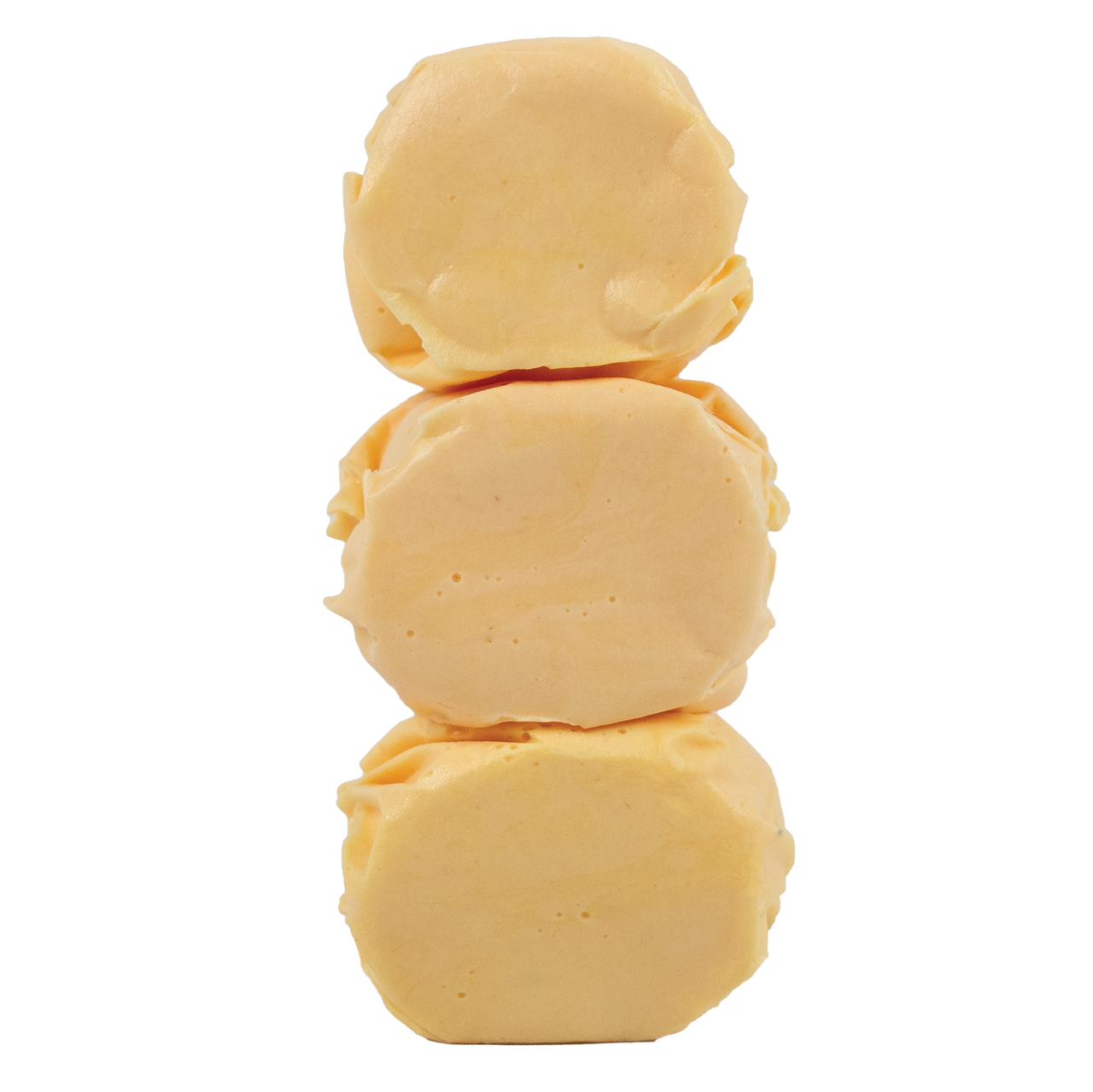 Close-up of three unwrapped Brigham City Peach Taffy candies stacked to show soft, whipped texture and creamy peach color