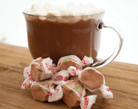 Hot Chocolate taffy candy from Taffy Town next to a mug of cocoa and marshmallows - festive salt water taffy in brown, red, and green colors.